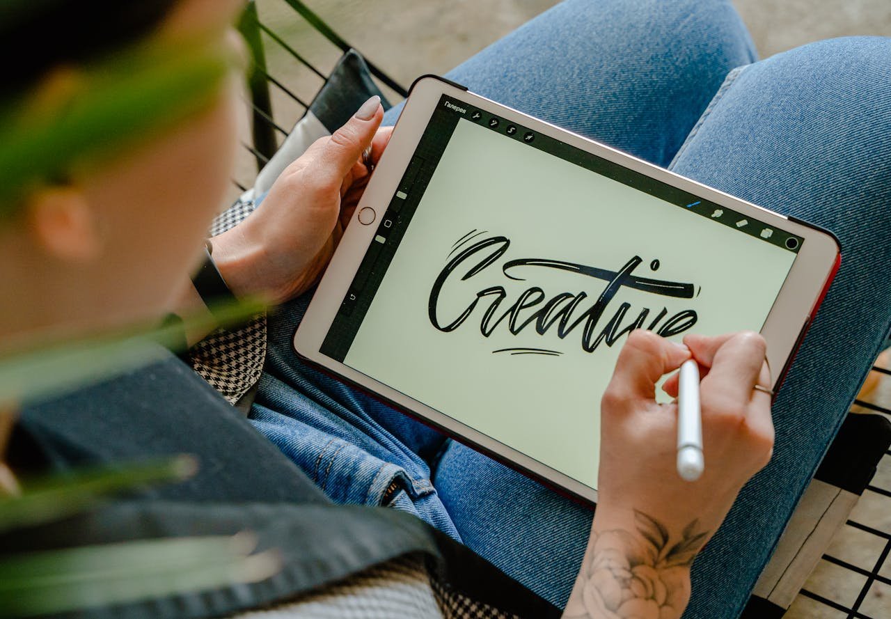 Person using stylus pen on tablet for digital lettering showing creativity in design.