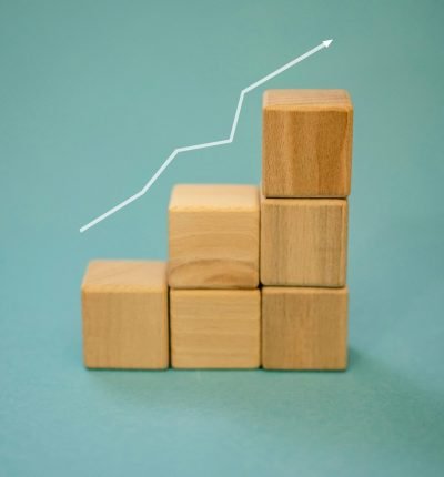 Wooden blocks forming a staircase with an upward arrow symbolizing growth and progress.
